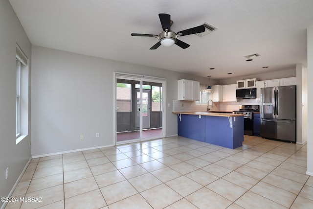 kitchen with hanging light fixtures, stainless steel appliances, wood counters, a kitchen breakfast bar, and white cabinets