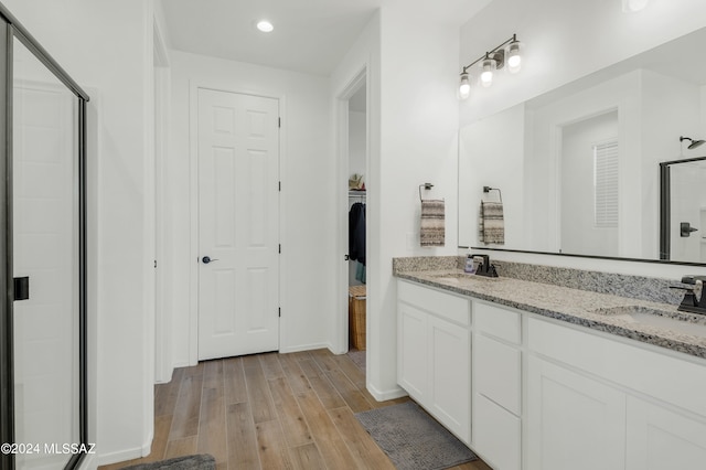 bathroom featuring an enclosed shower, double vanity, and wood-type flooring