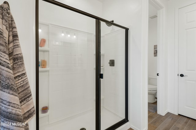 bathroom with toilet, hardwood / wood-style floors, and walk in shower