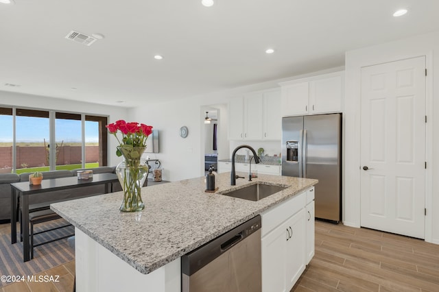 kitchen with sink, dishwashing machine, light stone countertops, a kitchen island with sink, and refrigerator