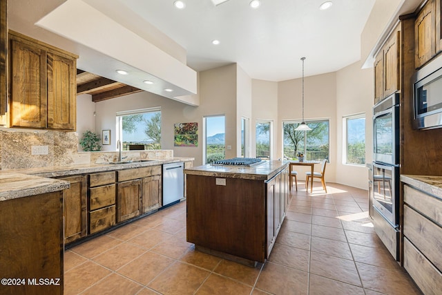 kitchen featuring sink, light tile patterned floors, appliances with stainless steel finishes, beamed ceiling, and a kitchen island