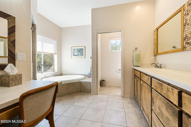 bathroom with tile patterned floors, a wealth of natural light, vanity, and a relaxing tiled tub