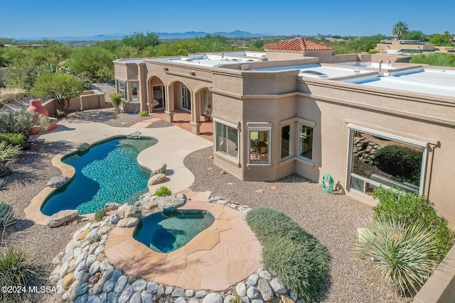 view of swimming pool featuring a patio area, a mountain view, and an in ground hot tub