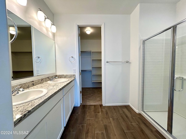 bathroom with wood-type flooring, vanity, and a shower with shower door