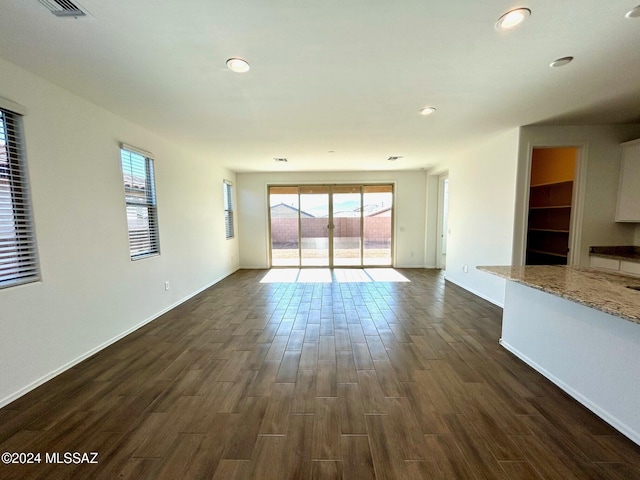 unfurnished living room featuring dark hardwood / wood-style flooring and plenty of natural light