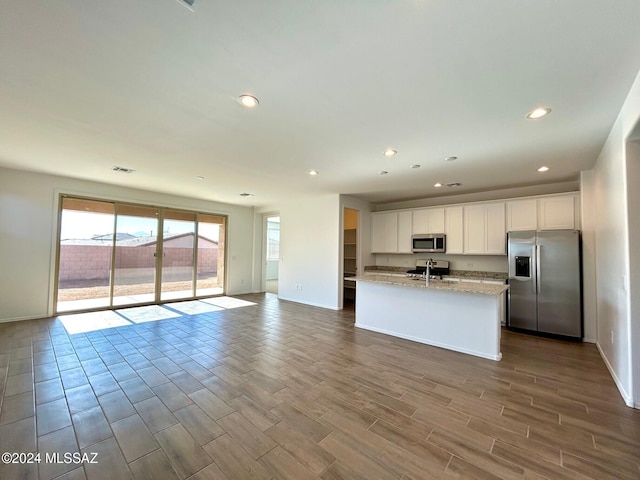 kitchen with a center island with sink, sink, light hardwood / wood-style flooring, white cabinetry, and stainless steel appliances