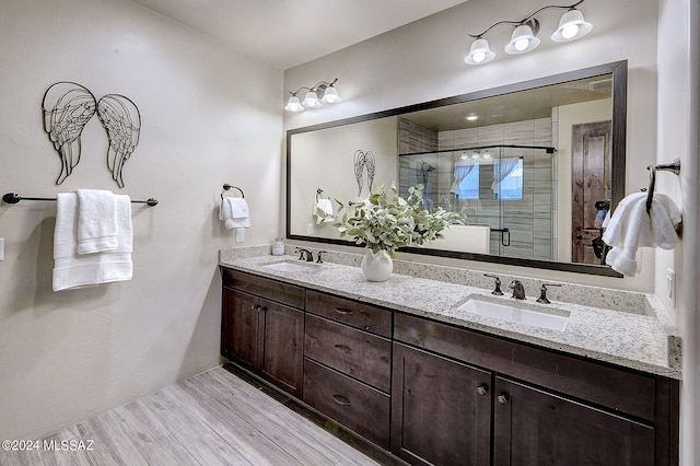 bathroom featuring an enclosed shower, wood-type flooring, and double sink vanity