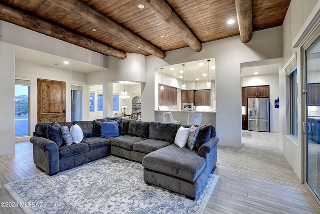 living room featuring wooden ceiling, a high ceiling, beamed ceiling, and light hardwood / wood-style flooring