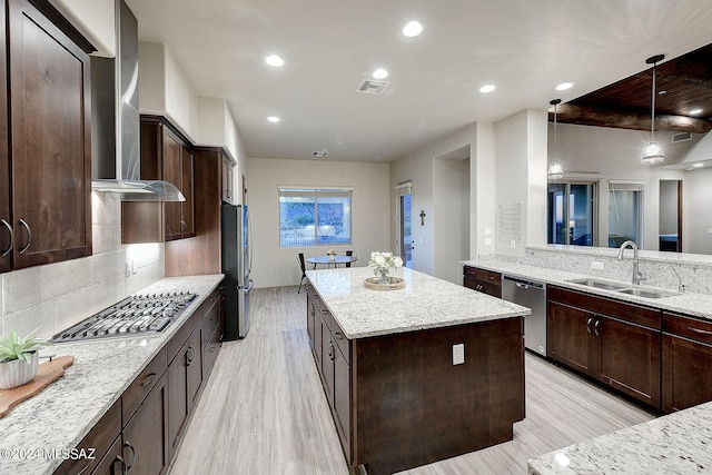 kitchen with tasteful backsplash, stainless steel appliances, a kitchen island, wall chimney exhaust hood, and sink