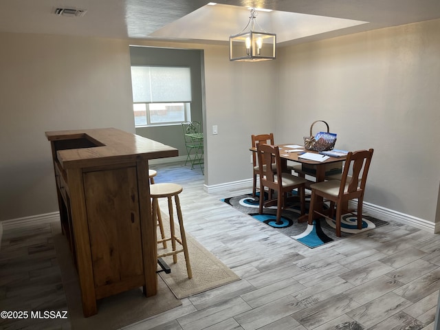 dining area with light hardwood / wood-style flooring and a notable chandelier