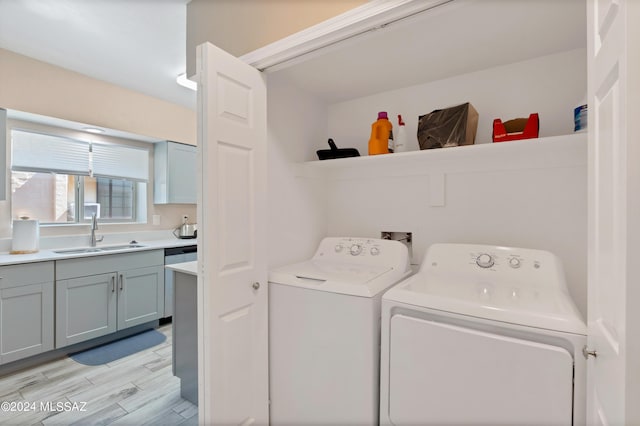 laundry room with light hardwood / wood-style floors, washer and clothes dryer, and sink