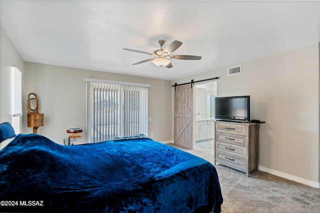 bedroom with light carpet, a barn door, ensuite bathroom, and ceiling fan