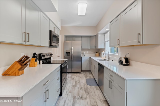 kitchen featuring gray cabinetry, light hardwood / wood-style floors, sink, and appliances with stainless steel finishes