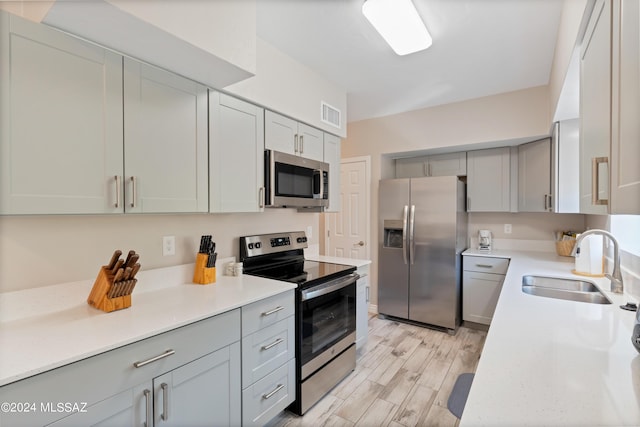 kitchen with gray cabinetry, sink, stainless steel appliances, and light hardwood / wood-style floors