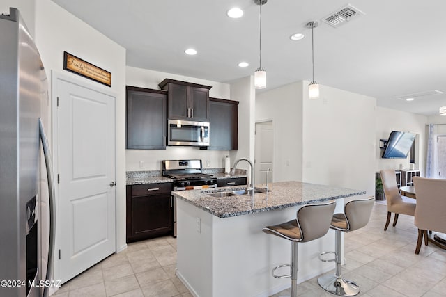 kitchen with stainless steel appliances, stone countertops, hanging light fixtures, sink, and light tile floors