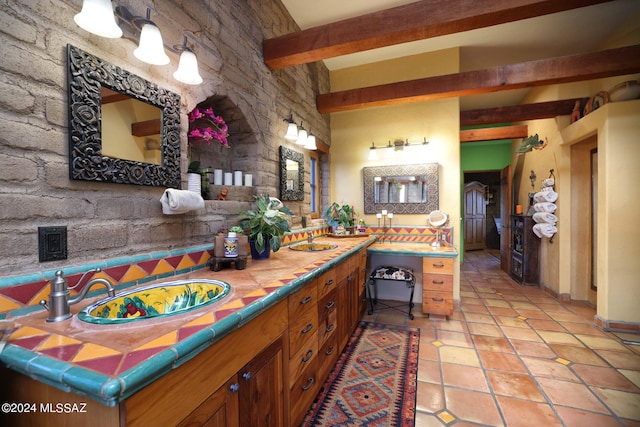 bathroom with tile patterned flooring, a sink, and beamed ceiling