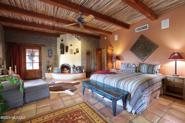 bedroom with a large fireplace, light tile patterned flooring, beam ceiling, and visible vents