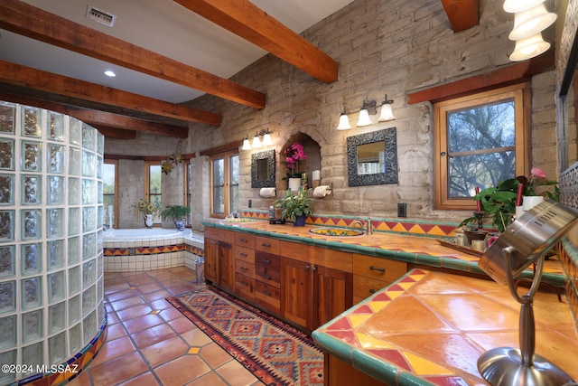 full bathroom featuring tile patterned flooring, visible vents, beam ceiling, a sink, and a wealth of natural light
