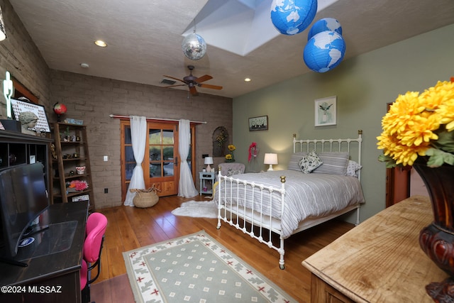 bedroom featuring wood-type flooring, recessed lighting, brick wall, and visible vents
