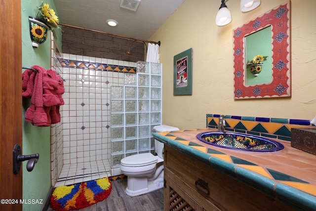 bathroom with walk in shower, vanity, toilet, wood finished floors, and visible vents