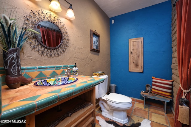 full bath featuring vanity, stone finish floor, and toilet