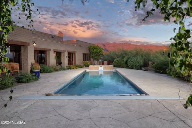 view of swimming pool featuring a patio area, a mountain view, and a pool with connected hot tub