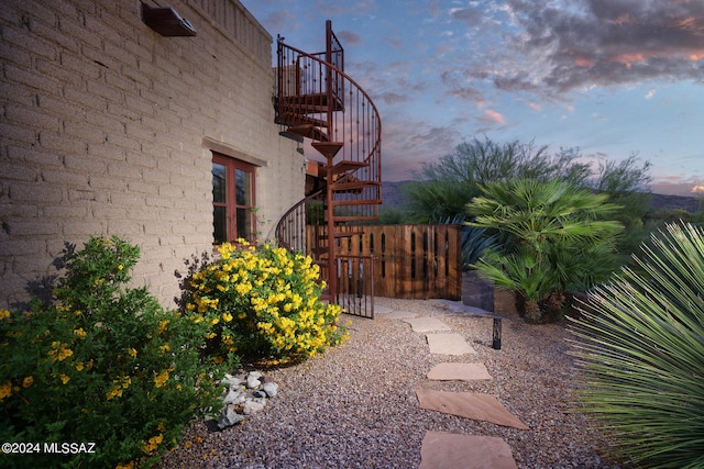 yard at dusk featuring fence and stairs