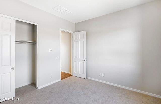 unfurnished bedroom featuring a closet and light colored carpet