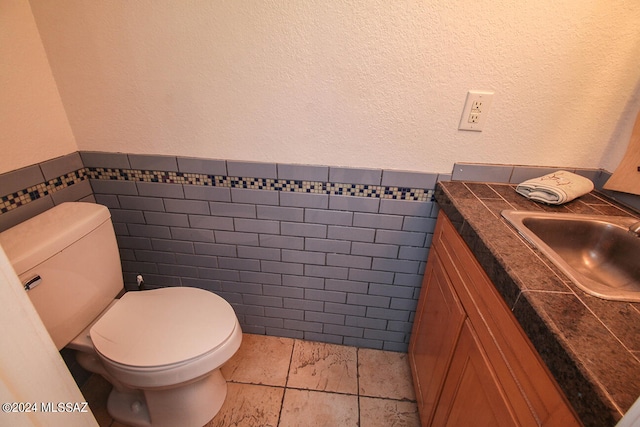 bathroom featuring vanity, tile walls, toilet, and tile patterned floors