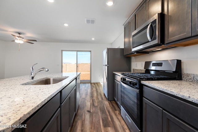 kitchen featuring dark hardwood / wood-style flooring, appliances with stainless steel finishes, light stone countertops, ceiling fan, and sink