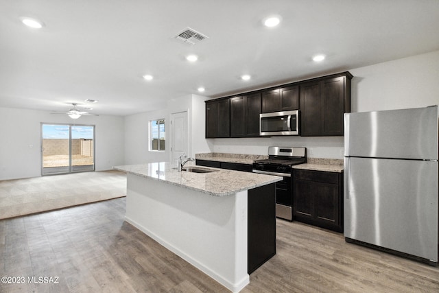 kitchen featuring light hardwood / wood-style floors, stainless steel appliances, ceiling fan, a kitchen island with sink, and sink