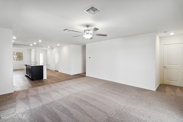 unfurnished living room featuring sink, carpet flooring, and ceiling fan