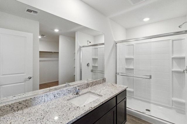 bathroom with walk in shower, vanity, and hardwood / wood-style floors