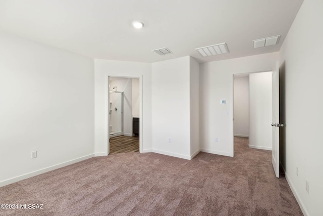 unfurnished bedroom featuring light colored carpet and ensuite bathroom