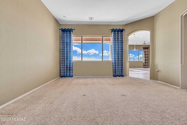 unfurnished room featuring light carpet, ceiling fan, and plenty of natural light