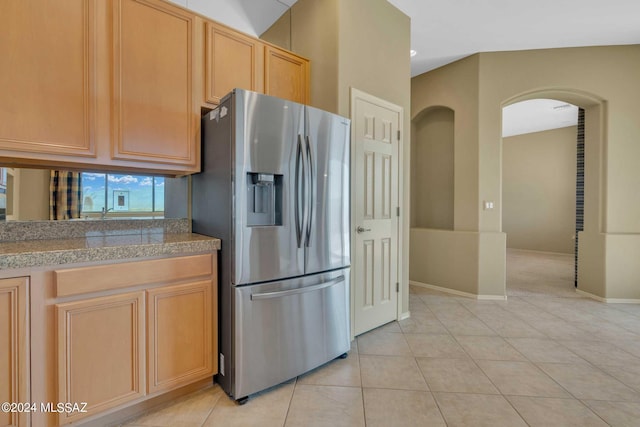 kitchen with stainless steel refrigerator with ice dispenser, light brown cabinetry, and light tile patterned flooring