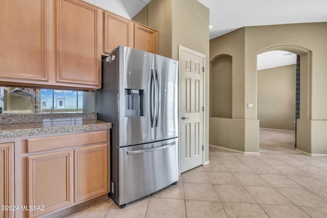 kitchen with light tile patterned floors, light brown cabinetry, and stainless steel fridge