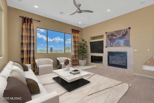 living room with ceiling fan, carpet flooring, and a tile fireplace