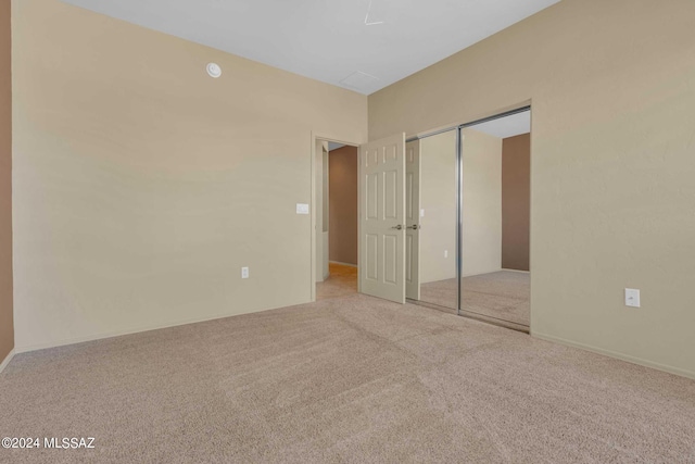 unfurnished bedroom with light colored carpet and a closet