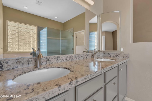 bathroom with a shower with shower door and vanity