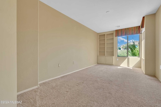 empty room with carpet floors and built in shelves