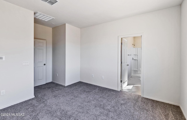 unfurnished bedroom with connected bathroom and dark carpet