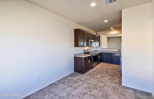 kitchen with dark brown cabinets, light stone countertops, and appliances with stainless steel finishes