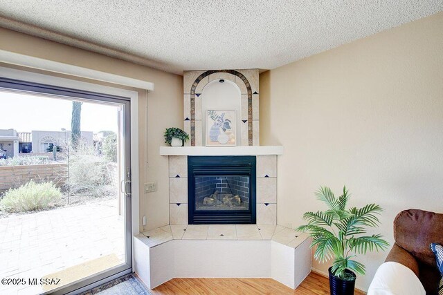 living room with ceiling fan, light hardwood / wood-style flooring, and a textured ceiling