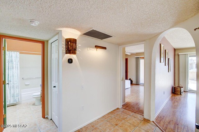 unfurnished living room featuring ceiling fan, light hardwood / wood-style flooring, and a textured ceiling