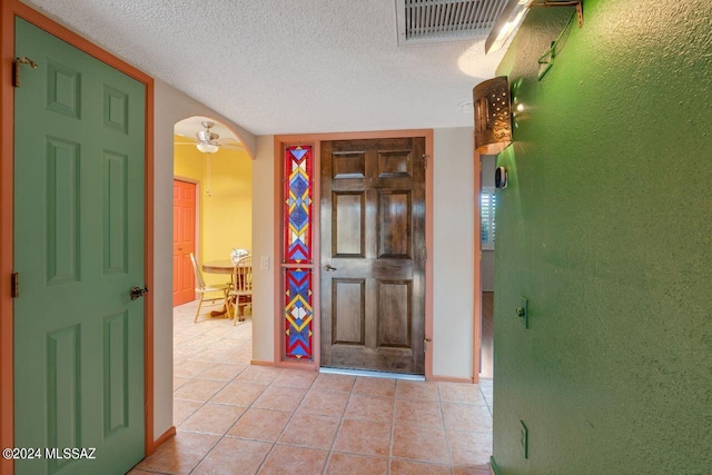 entrance foyer with light tile patterned floors, a textured ceiling, and ceiling fan