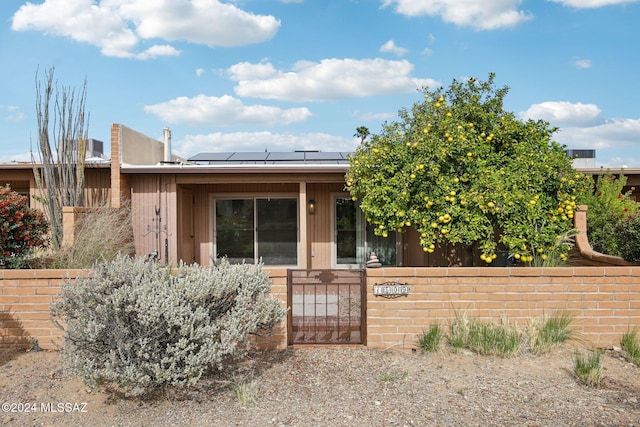 view of front of property featuring solar panels, a fenced front yard, metal roof, a standing seam roof, and a gate