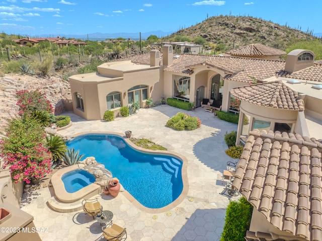 view of swimming pool featuring a mountain view, a patio, and an in ground hot tub