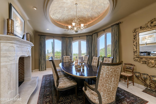 dining room with a chandelier, a tray ceiling, and a fireplace