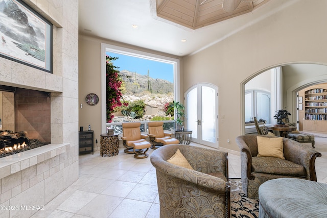 living room with a tile fireplace, a mountain view, french doors, and a towering ceiling